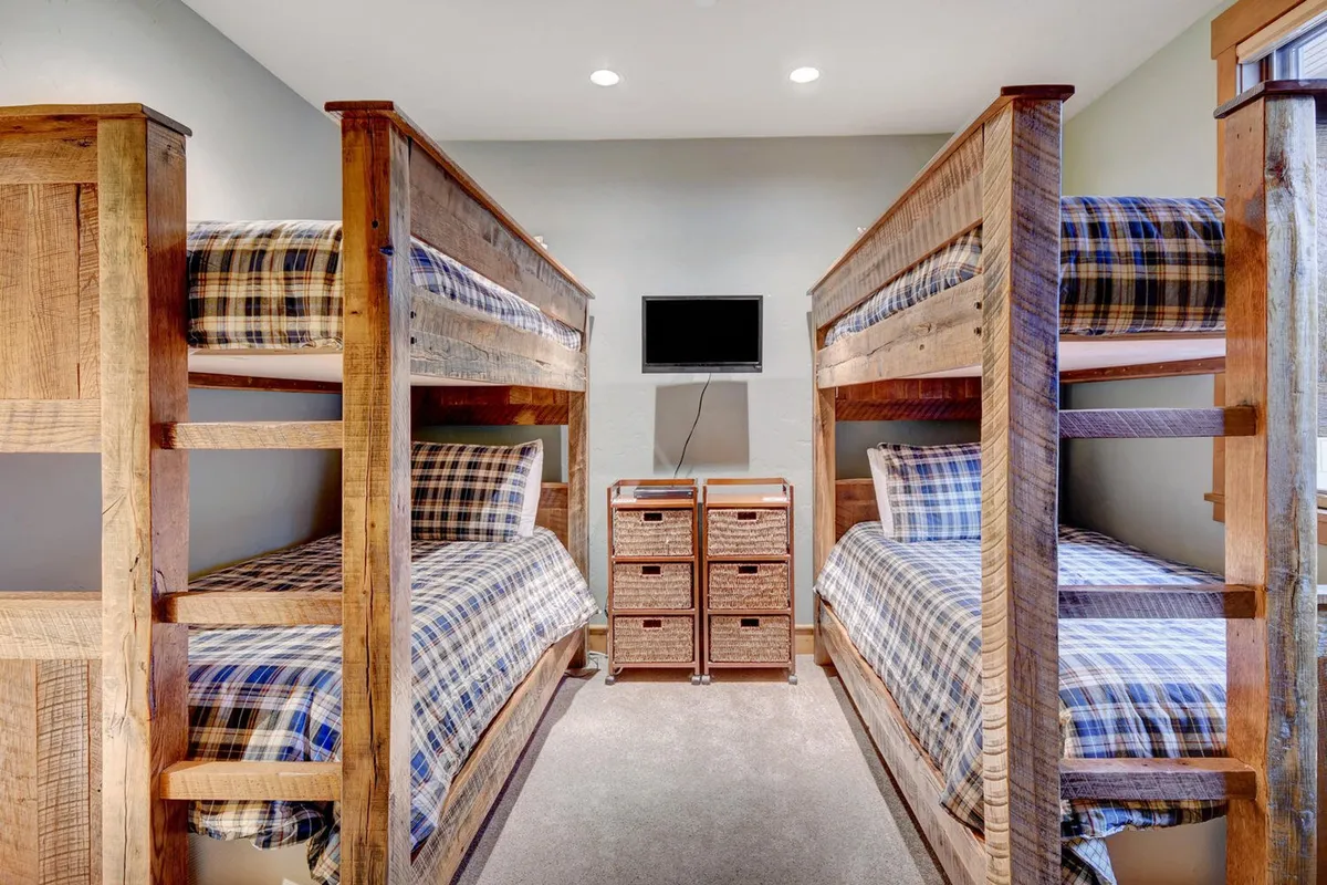 The scene features a playful bunk room with custom bunk beds, woven storage baskets, and plaid bedding. The setup evokes a sense of fun and comfort, making it perfect for kids or friends sharing a room.