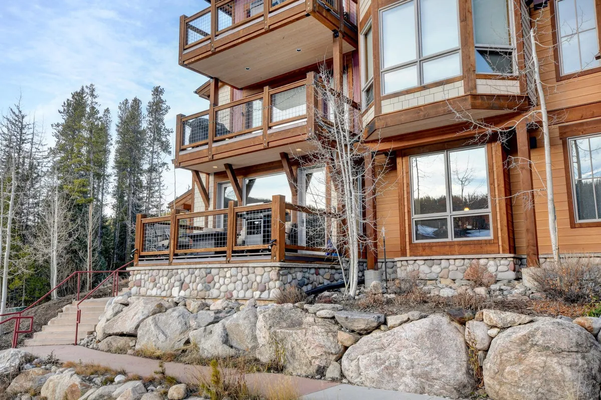 The image shows welcoming wooden balconies and a solid stone foundation nestled among trees. The view is peaceful, emphasizing relaxation and nature without close proximity to animals or pets.