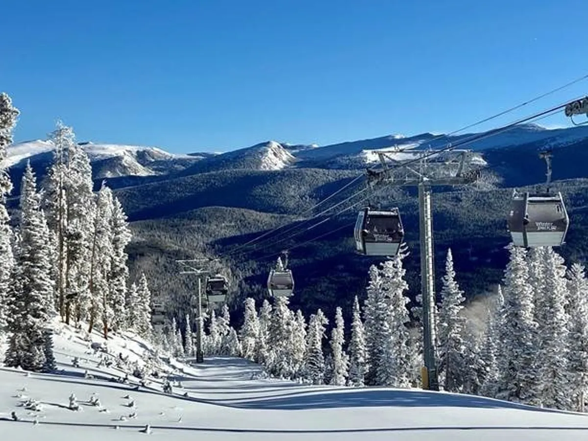 A scenic shot of ski lift gondolas gliding over snow-covered trees with a vast mountain backdrop. The setting feels both adventurous and peaceful, hinting at skiing, snowboarding, and scenic rides in the colder months.