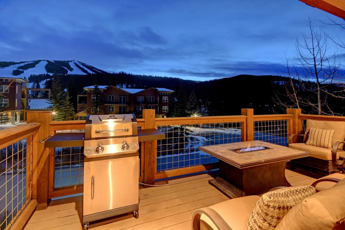 An inviting outdoor living area featuring a grill, fire pit, cozy seating, and expansive views of the mountains in the distance. The space offers a seamless connection to the natural surroundings and is ideal for relaxed social gatherings or unwinding after a day of adventure.