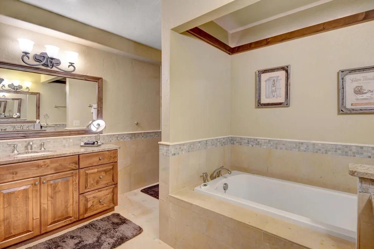 A serene bathroom with a vanity, large mirror, bathtub, and soft lighting. The design feels tranquil and spa-like, embodying relaxation and hotel-quality self-care routines.